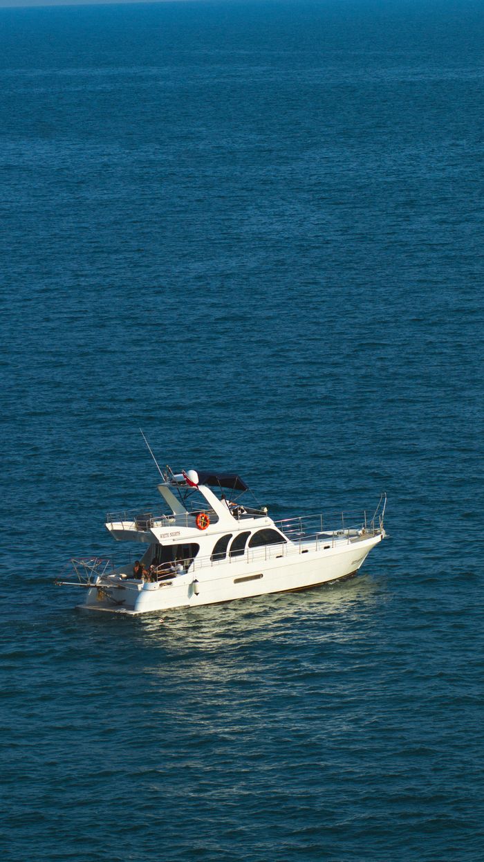A stunning white yacht sails on the tranquil blue sea near Antalya, Türkiye, epitomizing luxury and travel.