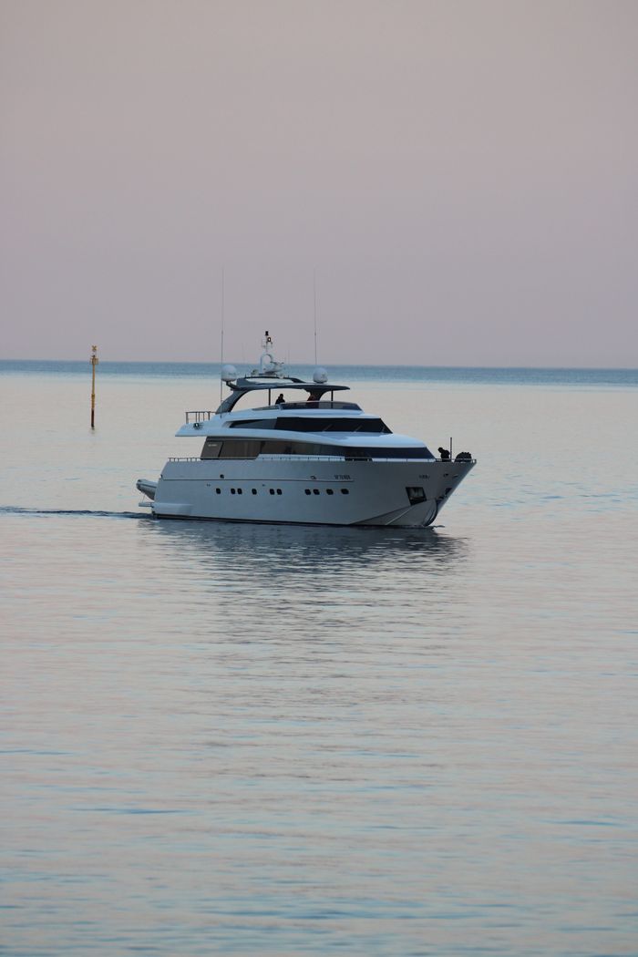 Elegant yacht cruises on serene waters near Portofino, Italy, during a tranquil sunset.