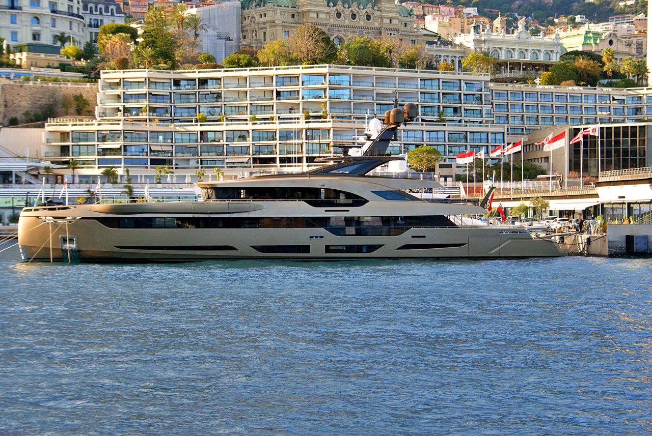 A luxury yacht moored at the picturesque Monaco harbor with modern waterfront architecture.