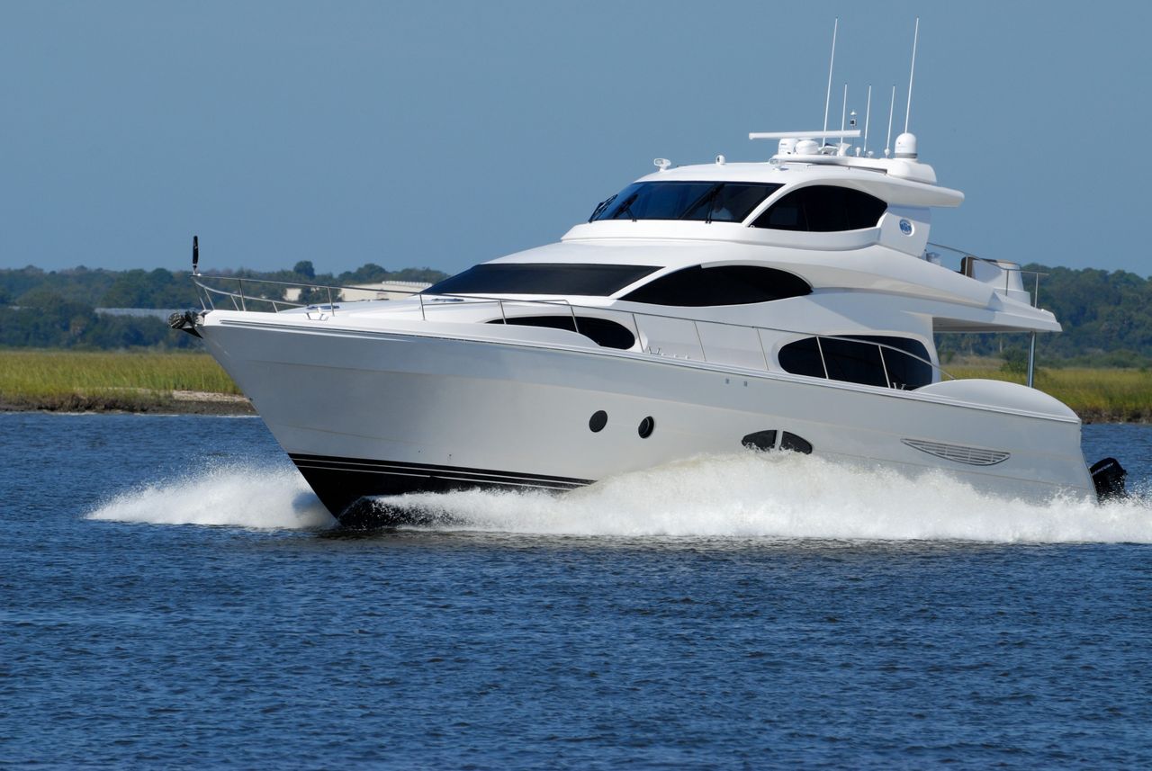 our-story A modern luxury yacht cruising swiftly on a calm river under a clear blue sky.