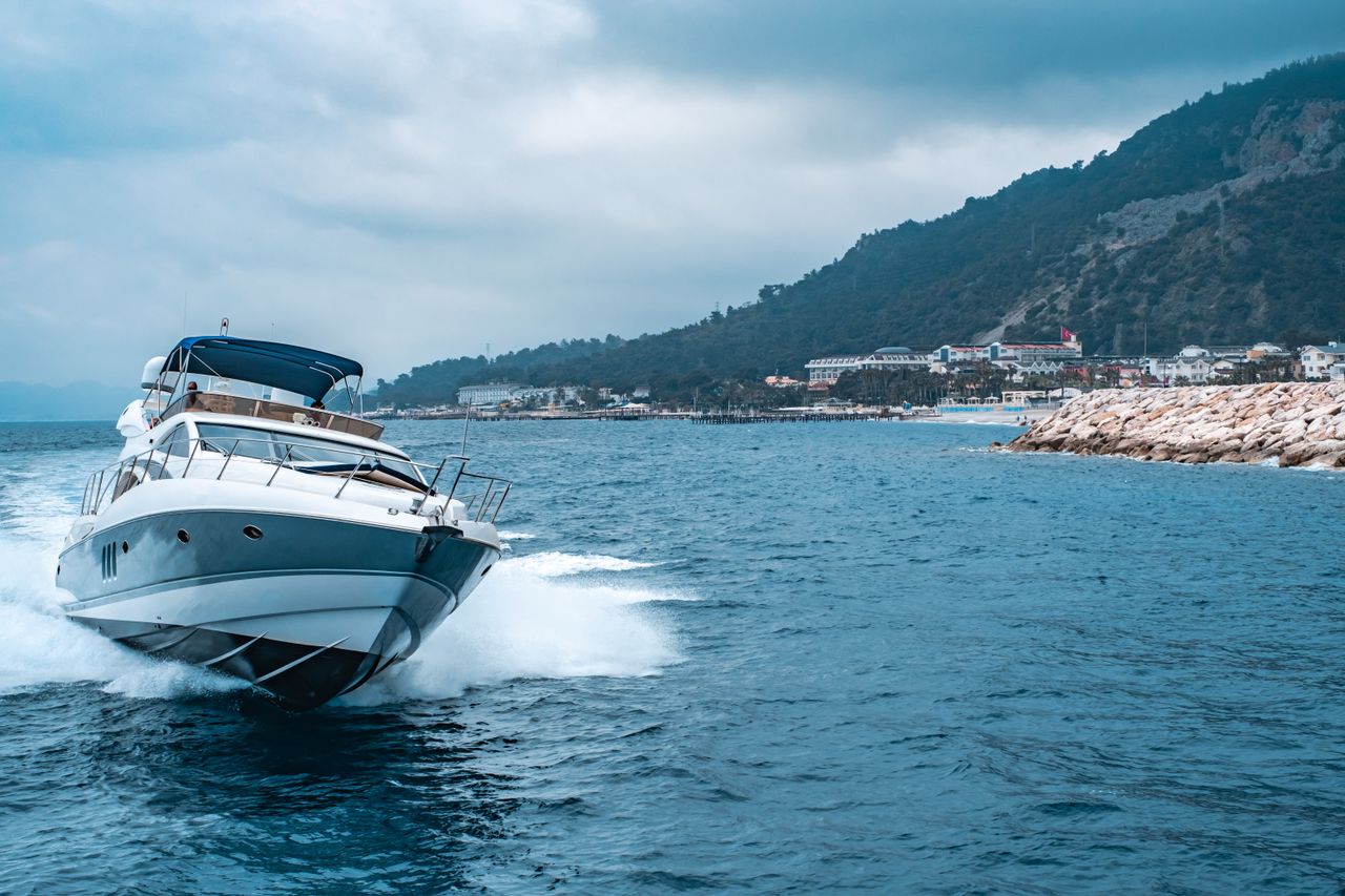 Services-01 A luxury yacht glides through the blue waters off the coast of Antalya, Türkiye, with scenic mountains in the background.